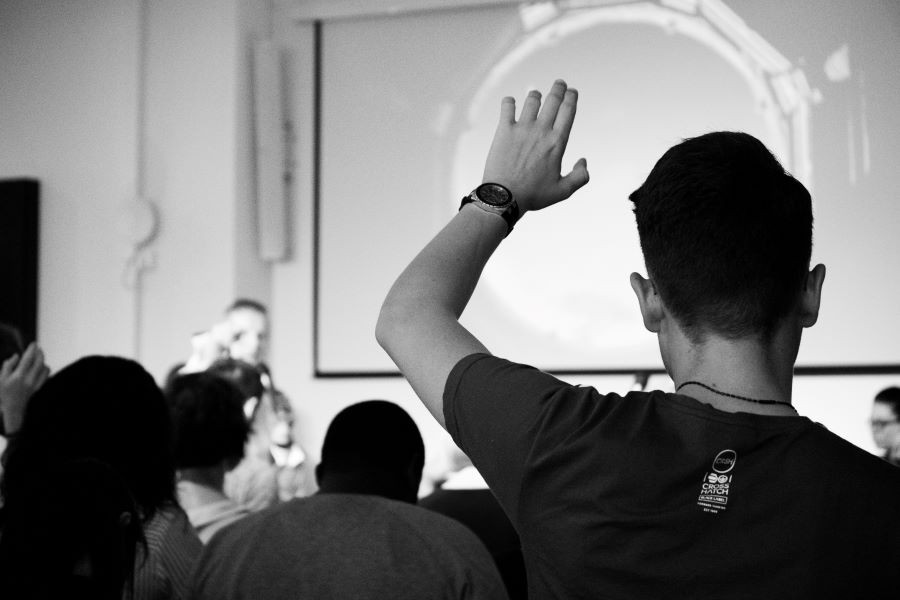 A student raising his hand in a classroom setting.