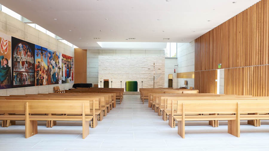 A house of worship with wooden benches, acoustic treatments, and AV equipment.